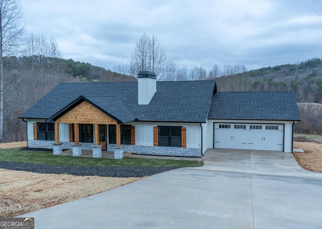 view of front of home with a chimney, a garage, driveway, and a shingled roof