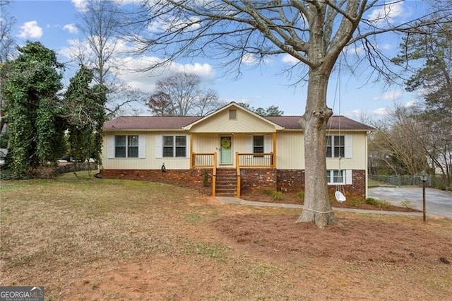 single story home featuring brick siding, a porch, and a front lawn