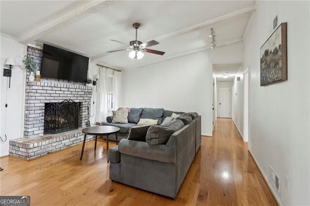 living area with visible vents, wood finished floors, a brick fireplace, and ceiling fan