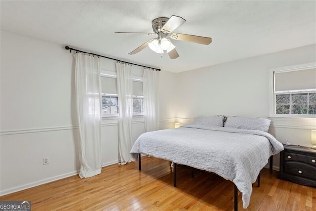 bedroom with a ceiling fan, baseboards, and wood finished floors