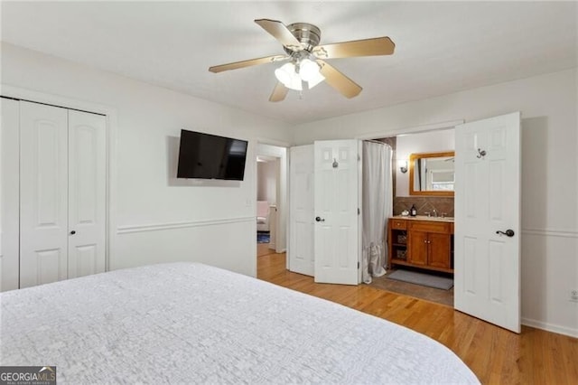 bedroom with a closet, ensuite bath, light wood-type flooring, and ceiling fan