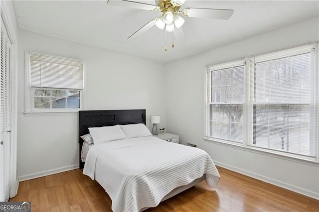 bedroom with ceiling fan, baseboards, and light wood-style floors