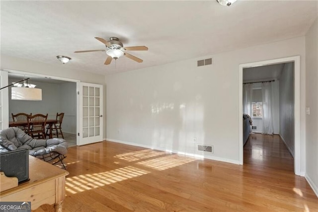 living area featuring wood finished floors, visible vents, and ceiling fan