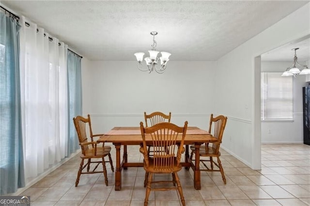 dining space featuring baseboards, a textured ceiling, an inviting chandelier, and light tile patterned flooring