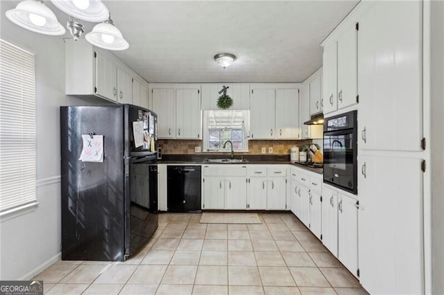 kitchen with black appliances, a sink, under cabinet range hood, backsplash, and dark countertops