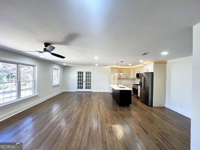 unfurnished living room with baseboards, dark wood-style floors, visible vents, and ceiling fan