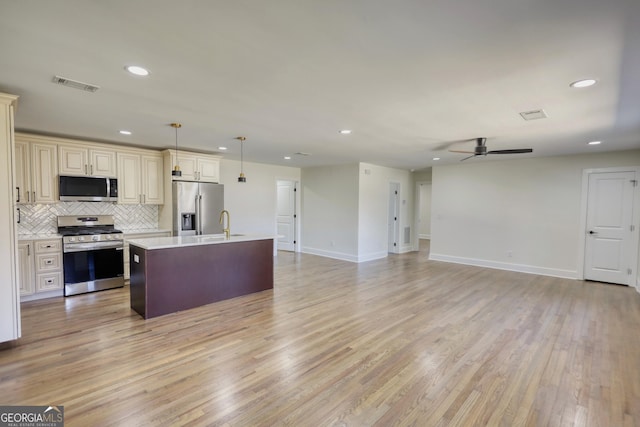 kitchen featuring visible vents, open floor plan, light countertops, appliances with stainless steel finishes, and cream cabinetry