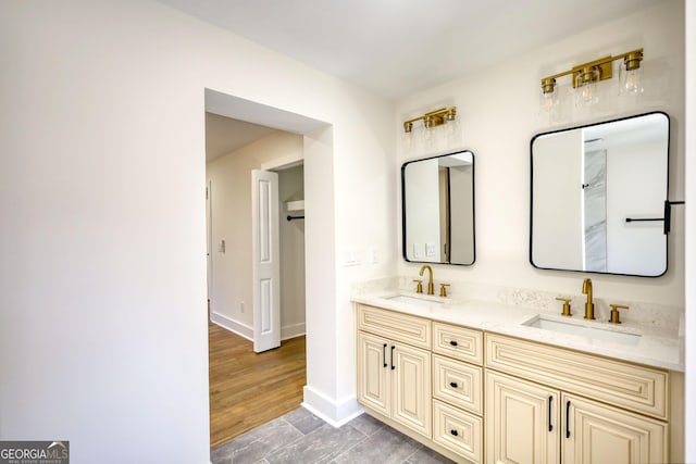 bathroom with a sink, baseboards, wood finished floors, and double vanity