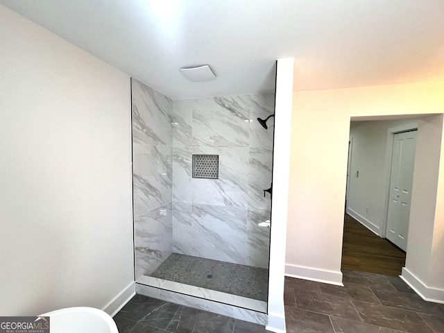 bathroom with baseboards, marble finish floor, and tiled shower