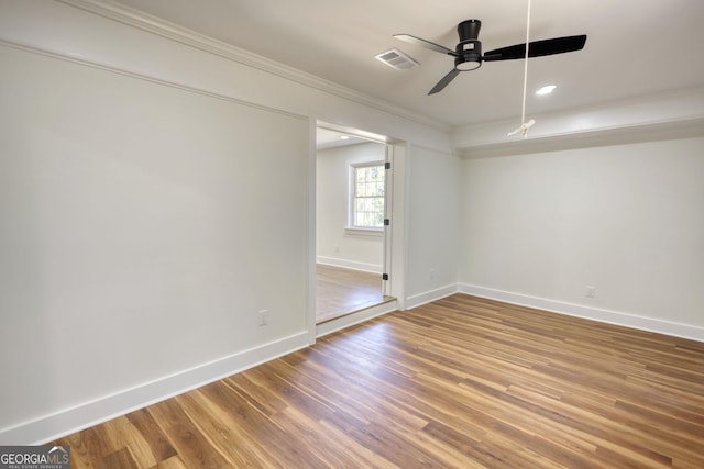 unfurnished room with visible vents, baseboards, ornamental molding, wood finished floors, and a ceiling fan