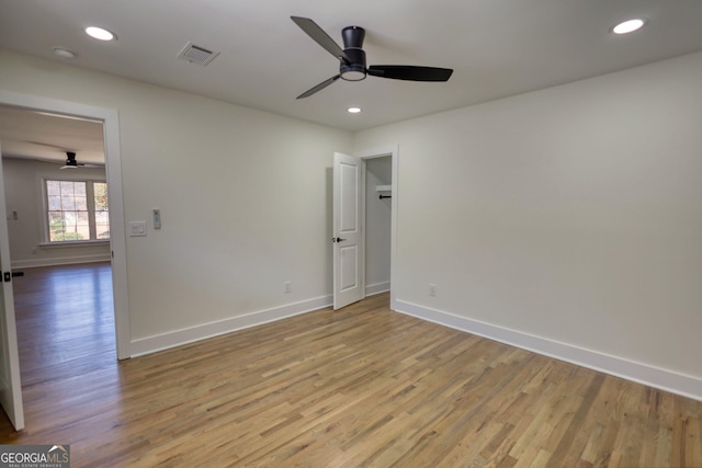 spare room featuring a ceiling fan, visible vents, light wood finished floors, and baseboards