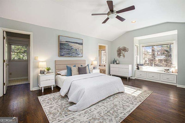 bedroom with ensuite bath, dark wood finished floors, baseboards, ceiling fan, and vaulted ceiling