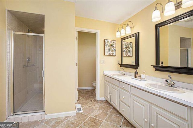 bathroom with double vanity, toilet, a stall shower, and a sink