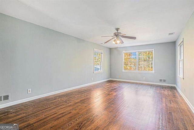 empty room featuring wood finished floors, a ceiling fan, visible vents, and baseboards