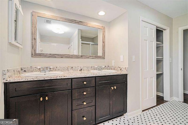 bathroom featuring double vanity, an enclosed shower, visible vents, and a sink