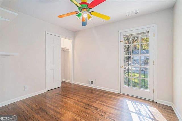 unfurnished bedroom with ceiling fan, wood finished floors, visible vents, and baseboards