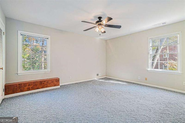 carpeted spare room with baseboards, visible vents, and ceiling fan