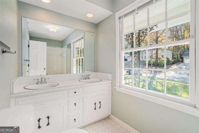 bathroom featuring a sink, baseboards, double vanity, and tile patterned floors