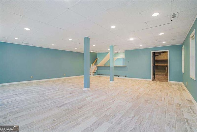 finished basement featuring stairway, visible vents, baseboards, and wood finished floors