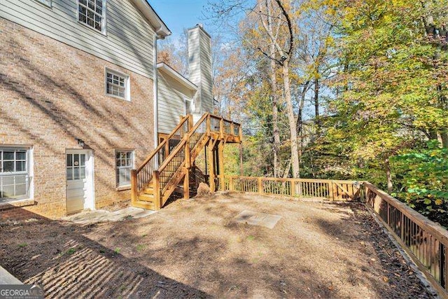 view of property exterior featuring a wooden deck, fence, a chimney, and stairway