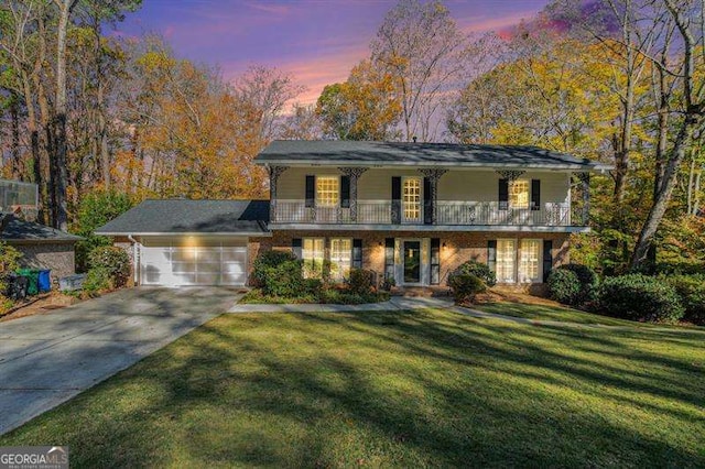 view of front facade with a garage, a balcony, concrete driveway, and a front yard