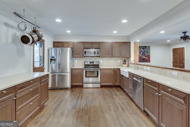 kitchen with backsplash, appliances with stainless steel finishes, wood finished floors, and a sink