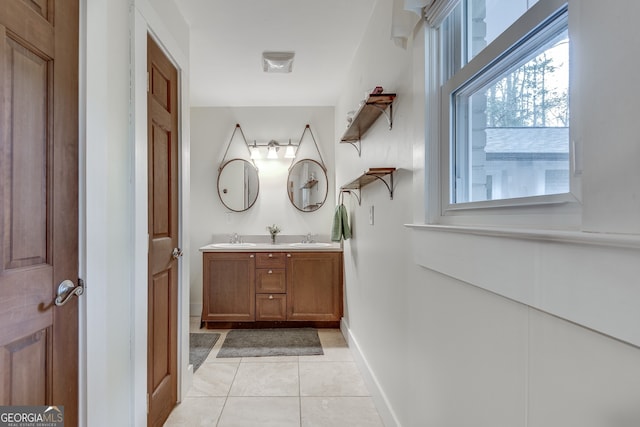 bathroom with tile patterned flooring, double vanity, baseboards, and a sink