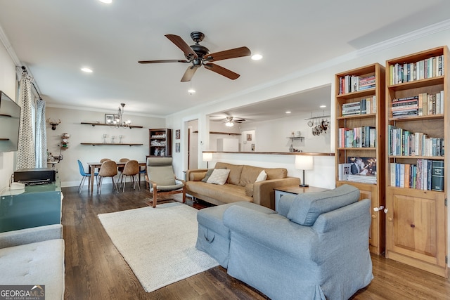 living area with ceiling fan with notable chandelier, wood finished floors, recessed lighting, crown molding, and baseboards