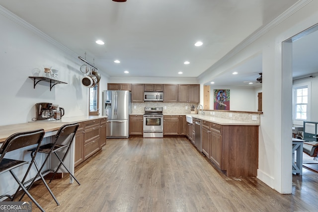 kitchen featuring decorative backsplash, wood finished floors, a ceiling fan, and stainless steel appliances