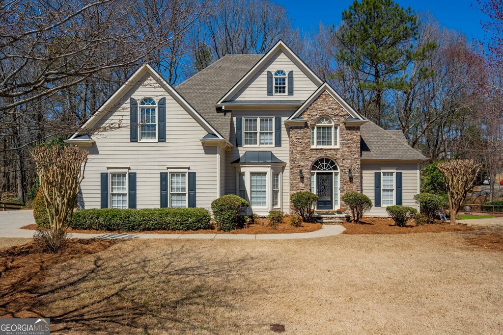 traditional-style home with stone siding and roof with shingles