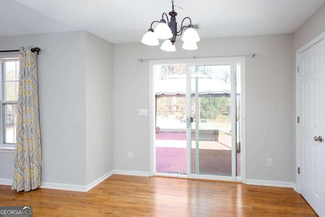 interior space featuring light wood-style floors, baseboards, a notable chandelier, and visible vents