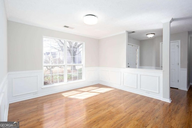 unfurnished room with crown molding, wood finished floors, and visible vents