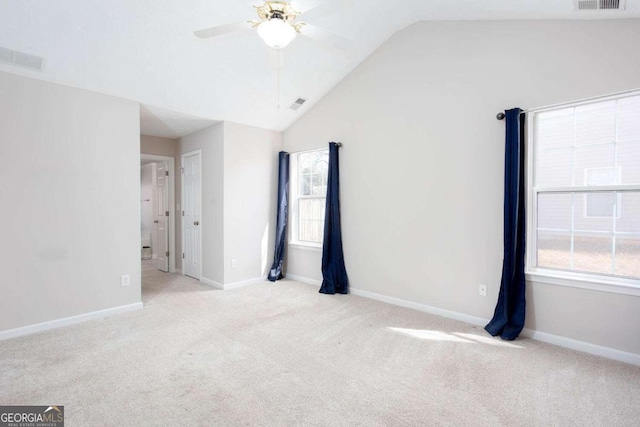 spare room featuring carpet flooring, visible vents, lofted ceiling, and a ceiling fan