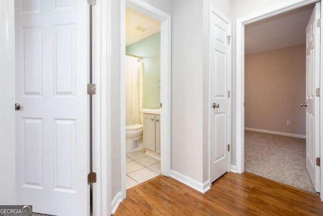 corridor featuring baseboards and wood finished floors