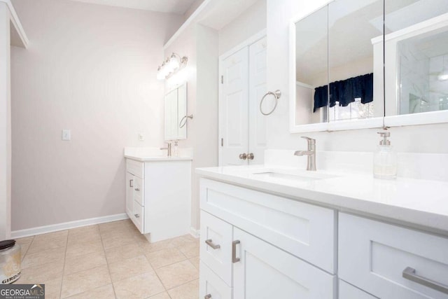 full bath featuring a sink, baseboards, two vanities, and tile patterned flooring