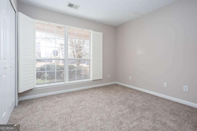 unfurnished room with a wealth of natural light, baseboards, visible vents, and carpet floors