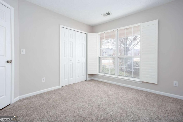 unfurnished bedroom with a closet, visible vents, baseboards, and carpet