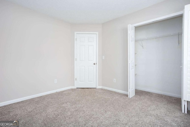 unfurnished bedroom featuring carpet, baseboards, a closet, and a textured ceiling