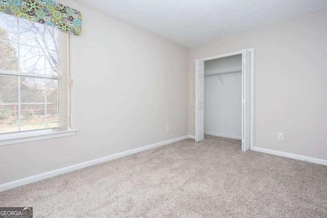 unfurnished bedroom with baseboards, carpet floors, a textured ceiling, and a closet