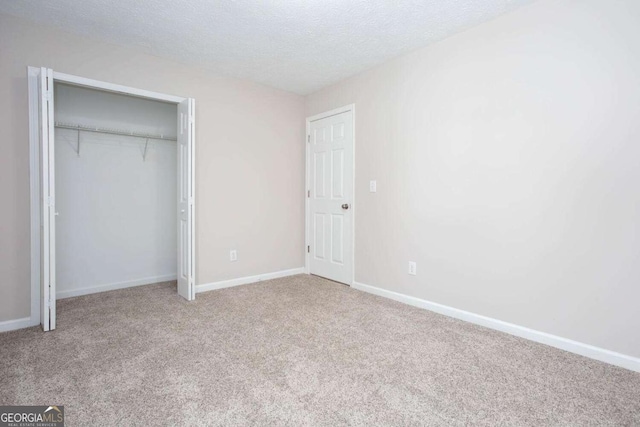 unfurnished bedroom featuring carpet, baseboards, a closet, and a textured ceiling