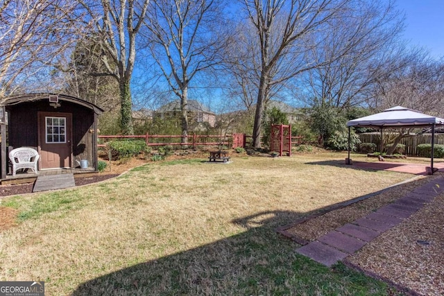 view of yard featuring a gazebo, a fenced backyard, a storage unit, and an outdoor structure