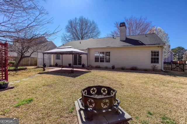 back of property featuring an outdoor fire pit, a gazebo, a chimney, a yard, and a patio