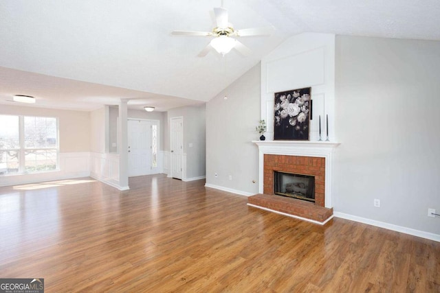 unfurnished living room with light wood-type flooring, lofted ceiling, a brick fireplace, and a ceiling fan