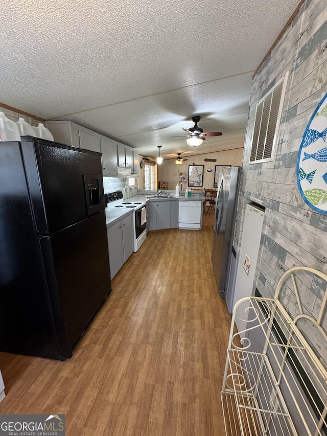 kitchen with a peninsula, electric range, freestanding refrigerator, dishwasher, and black refrigerator with ice dispenser