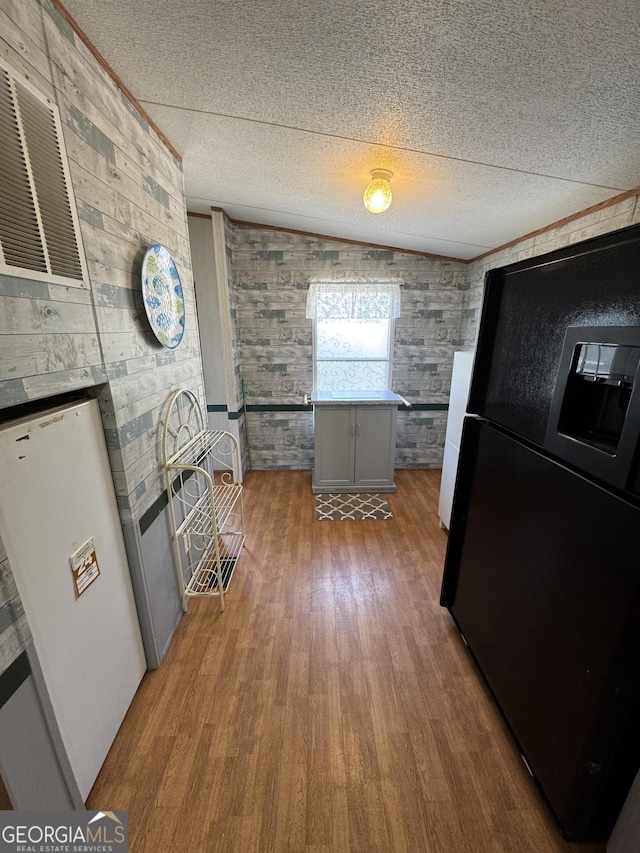 kitchen with gray cabinetry, a textured ceiling, freestanding refrigerator, and wood finished floors