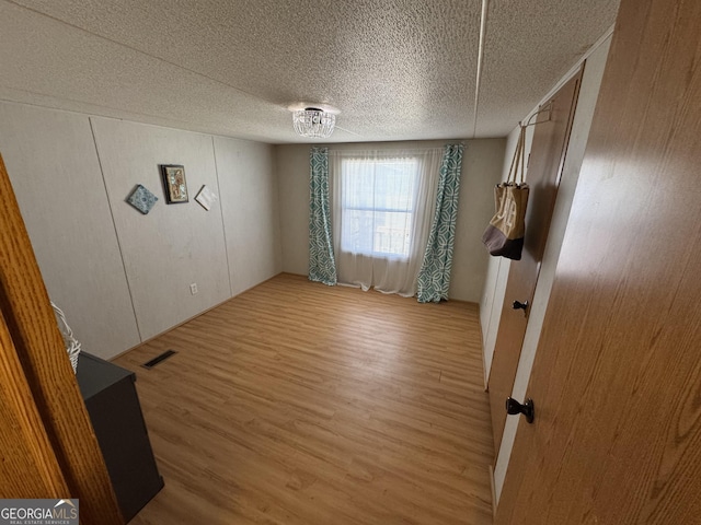 unfurnished bedroom featuring visible vents, a textured ceiling, and light wood-style flooring