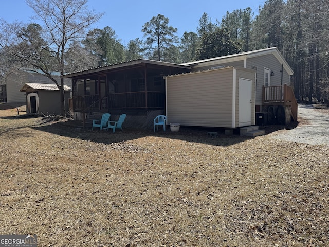 back of property featuring an outdoor structure and a sunroom