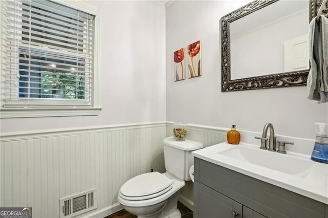 bathroom featuring a wainscoted wall, toilet, vanity, and visible vents