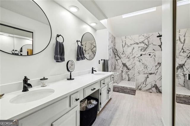 bathroom with double vanity, wood finished floors, a marble finish shower, and a sink