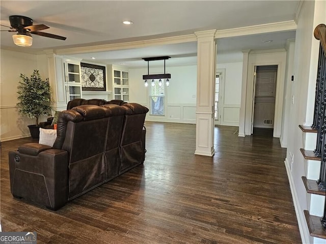 living room with a wainscoted wall, a ceiling fan, dark wood finished floors, a decorative wall, and decorative columns